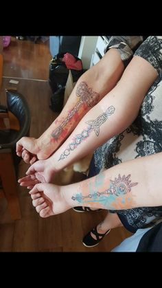 two people with tattoos on their legs sitting next to each other