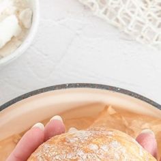 a person holding a pastry in their hand over a bowl of ice cream and sugar