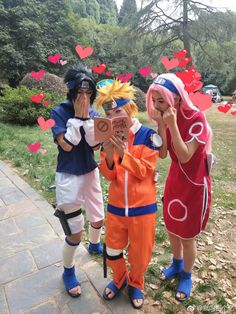 three people dressed up in costumes standing next to each other with hearts flying above them