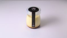 a glass jar filled with yellow liquid sitting on top of a white table next to a black ribbon