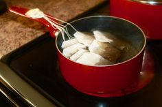 a red pot filled with marshmallows on top of a stove