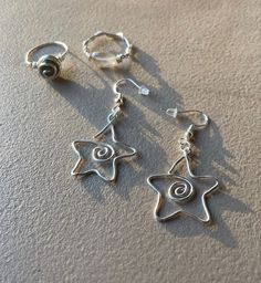 two silver earrings with star charms on them