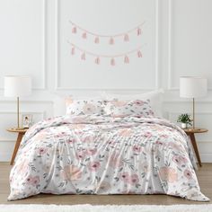 a bed with pink and white flowers on it in a room next to a wall