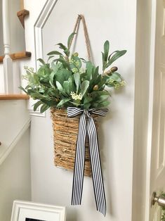 a plant hanging from the side of a wall with a bow on it's front door