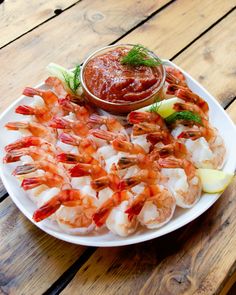 a white plate topped with shrimp next to a dipping sauce