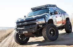 a silver truck parked on top of a dirt road