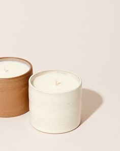 two candles sitting next to each other on a white surface with one candle in the middle