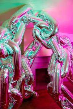 an inflatable balloon sculpture is displayed on a wooden floor next to a pink wall