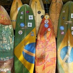 several surfboards are lined up in a row on the wall, with stickers attached to them