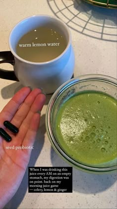 a person holding their hand next to a bowl of green liquid and a cup of coffee