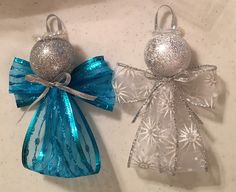 two silver and blue angel ornaments on a white counter top, one with a bow