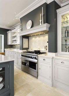 a large kitchen with white cabinets and silver stove top oven in the middle of it