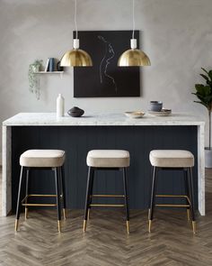 three stools are sitting in front of a bar with two paintings on the wall