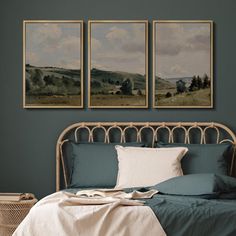 a bed with two paintings on the wall above it and a wicker basket underneath