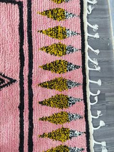 a pink rug with black and yellow designs on it