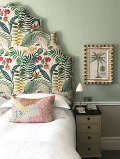 a bed with a colorful headboard and pillows on it's sides in a bedroom