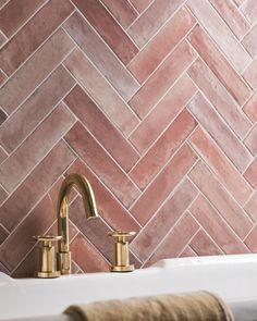 a bathroom sink with gold faucet and pink tiles on the wall behind it