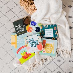 several children's books laid out on the floor next to a basket and blanket