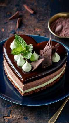 a heart shaped chocolate cake on a blue plate with mint garnish and whipped cream