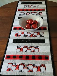 a table runner with red and black ornaments in a bowl on top of the placemat