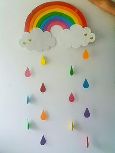 a white wall with rainbows and clouds hanging from it's sides in the shape of rain drops