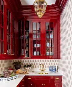 a kitchen with red cabinets and white counter tops, gold trim on the door knobs