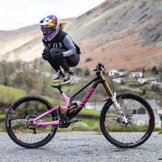 a person on a pink bike jumping in the air with mountains in the back ground