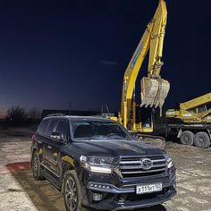 a black suv is parked in front of a crane