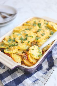 a casserole dish with potatoes and meat in it on a checkered cloth