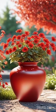 a red vase with flowers in it sitting on the ground