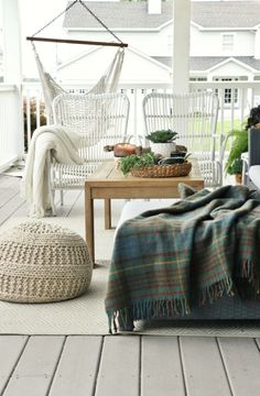 the porch is decorated with white wicker furniture and plaid blankets, including a hammock