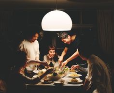 a group of people standing around a table with plates of food in front of them