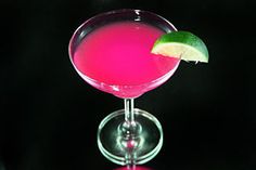 a close up of a drink in a wine glass with a lime slice on the rim