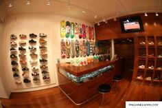 the inside of a shoe shop with lots of shoes on display and a television mounted to the wall