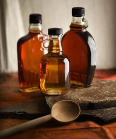 three bottles of maple syrup on a wooden table