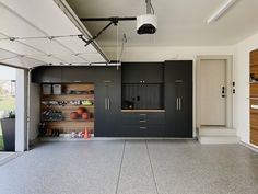 an empty garage with black cabinets and white flooring on the outside wall, along with hanging lights