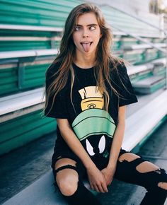 a woman sitting on the bleachers making a funny face with her tongue out