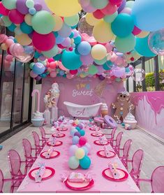 a table set up for a baby shower party with lots of balloons and pastel colors