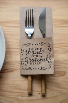 there is a napkin and fork on top of the table with a sign that says give thanks to the grateful people