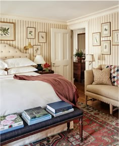 a bed sitting in a bedroom next to a chair and table with books on it