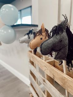 three horse head heads on top of wooden slats with balloons in the back ground