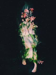 a woman with flowers on her head is surrounded by leaves and flowers in the dark