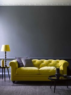 a living room with a yellow couch and two lamps on either side of the couch