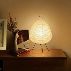 a lamp sitting on top of a wooden table next to a vase with flowers in it