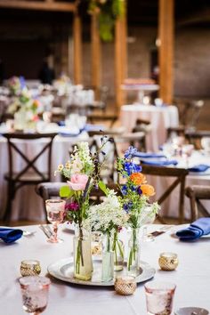 the tables are set with vases and flowers on them for an elegant dinner party