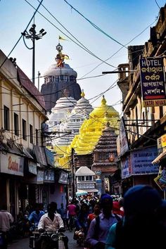 many people are walking down the street in front of some buildings with yellow decorations on them