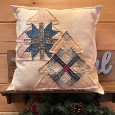 a decorative pillow on a wooden bench with pine cones and evergreen branches in the foreground