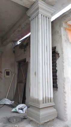 an unfinished room with a white column and window