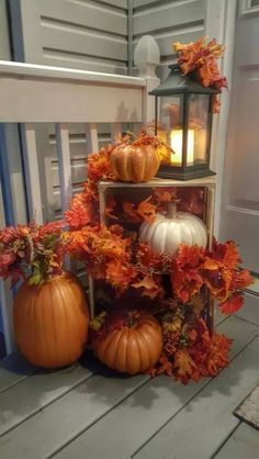 three pumpkins sitting on top of a wooden table next to a lantern and flowers