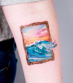 a painting on the arm of a woman with a frame around her body and an ocean wave in the background